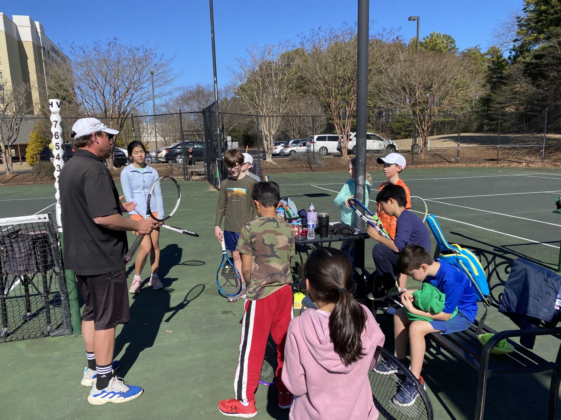 Mark briefing a group of junior players courtside before a lesson